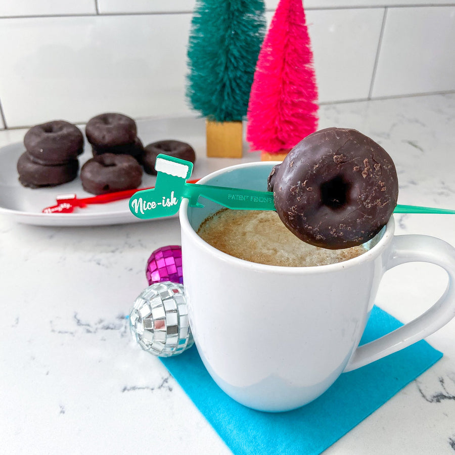 Santa's List themed cocktail pick Swizzly with mini donut garnish on a mug of coffee
